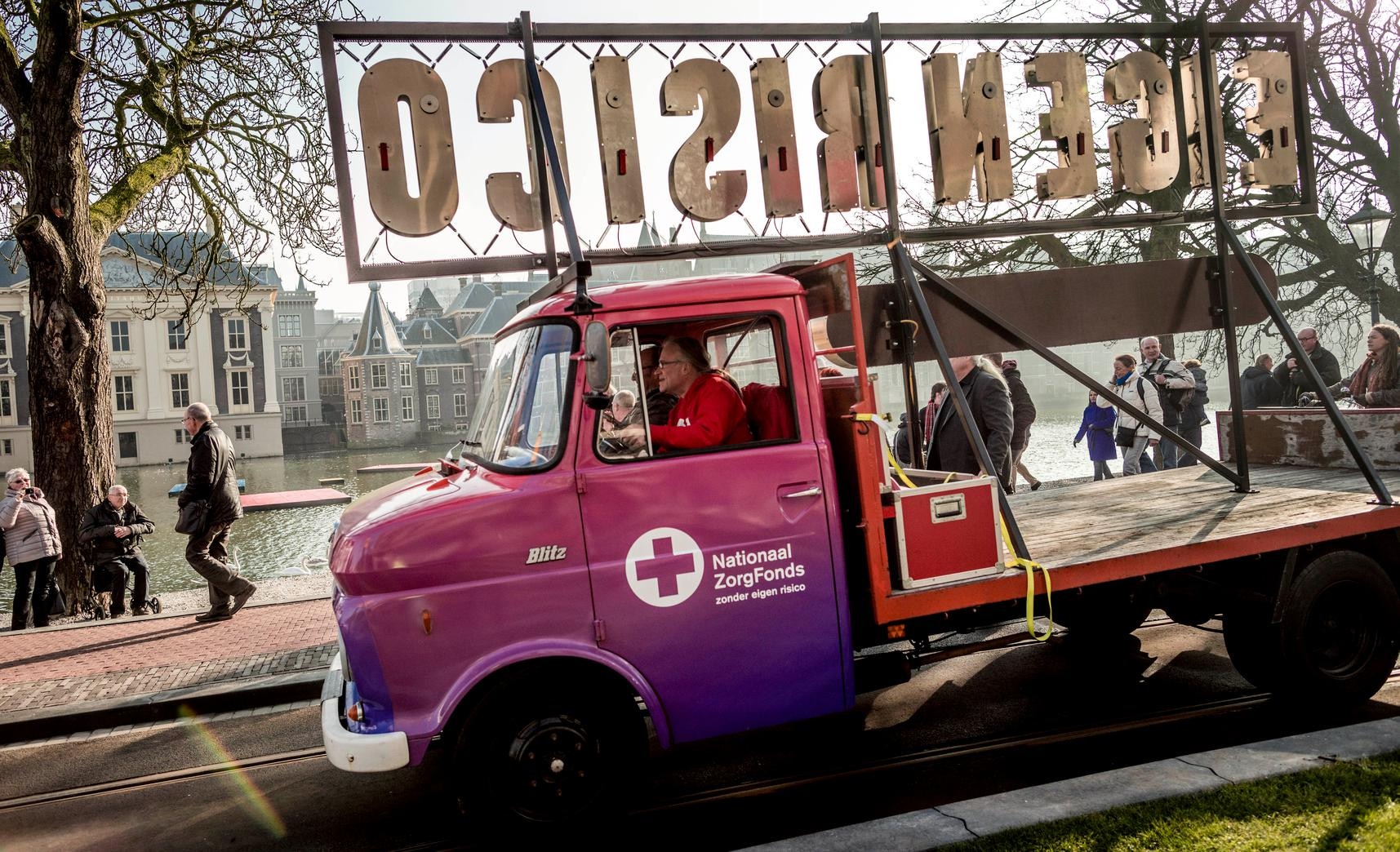 Een auto met de tekst 'Eigen Risico' passeert het torentje in Den Haag in februari 2017, tijdens een manifestatie voor de oprichting van een Nationaal Zorg Fonds.