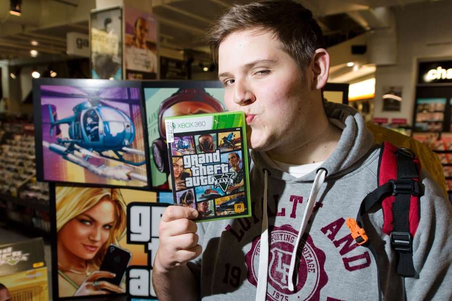 Een gamer in 2013 met zijn net gekochte spel Grand Theft Auto 5, toen nog voor de Xbox 360, Microsofts  oude spelcomputer.