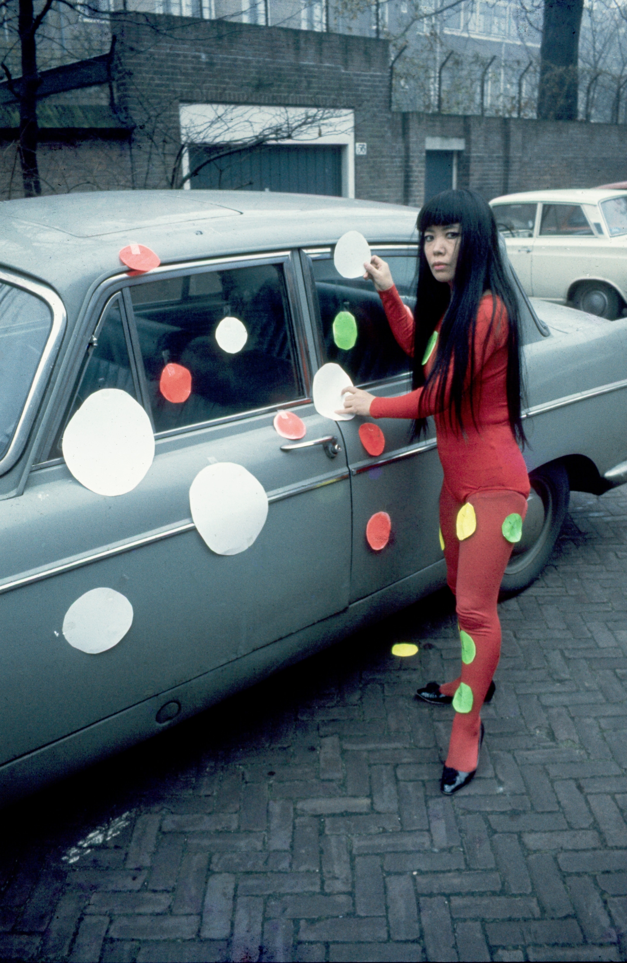 Yayoi Kusama beplakt auto’s met haar karakteristieke stippen, Den Haag, 1970.