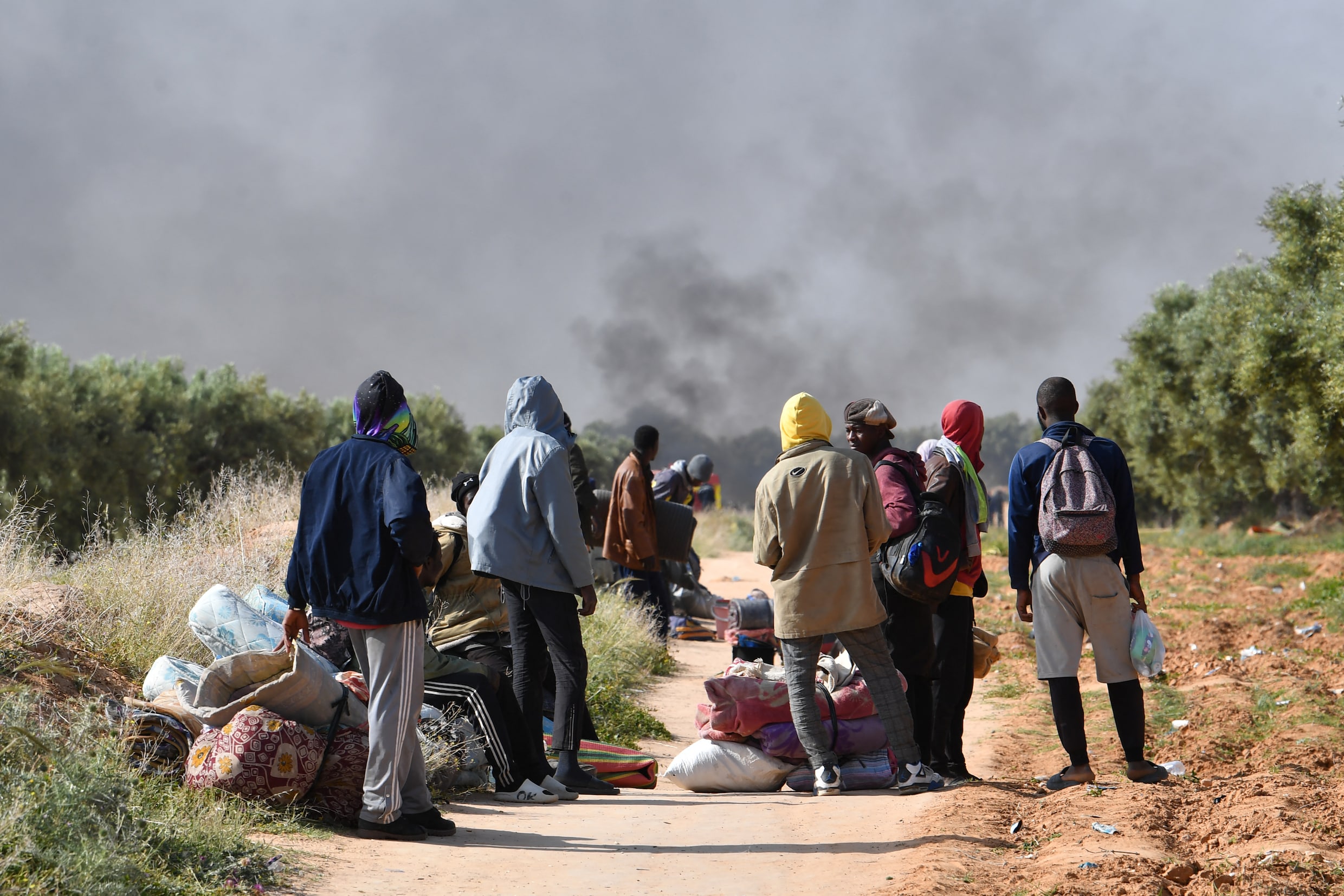 Migranten verlaten met hun bezittingen een kamp voor ongedocumenteerden in Tunesië.