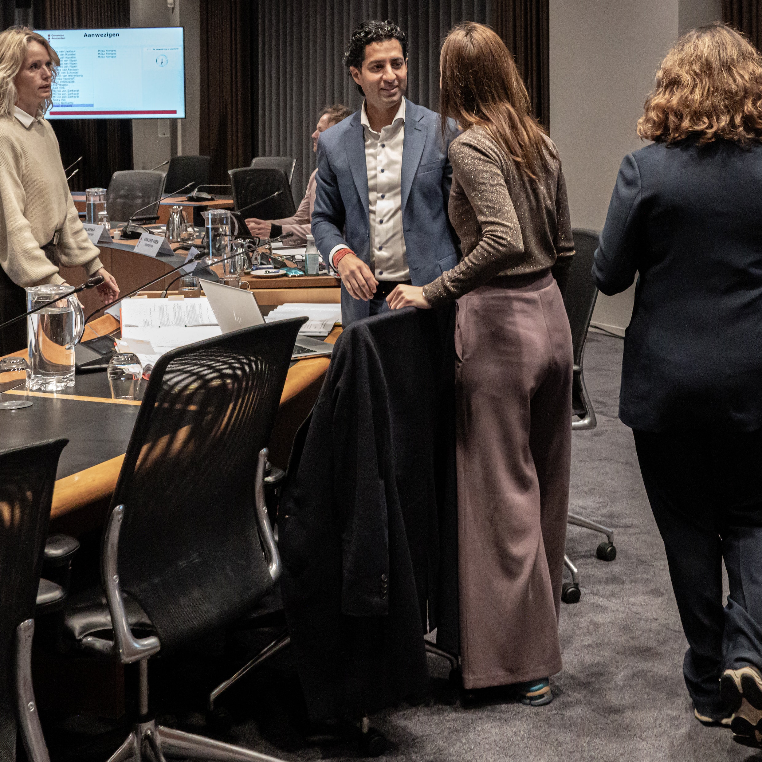 Ombudsman Munish Ramlal (midden) in de raadszaal van de Amsterdamse gemeenteraad. Rechts loopt burgemeester Femke Halsema.