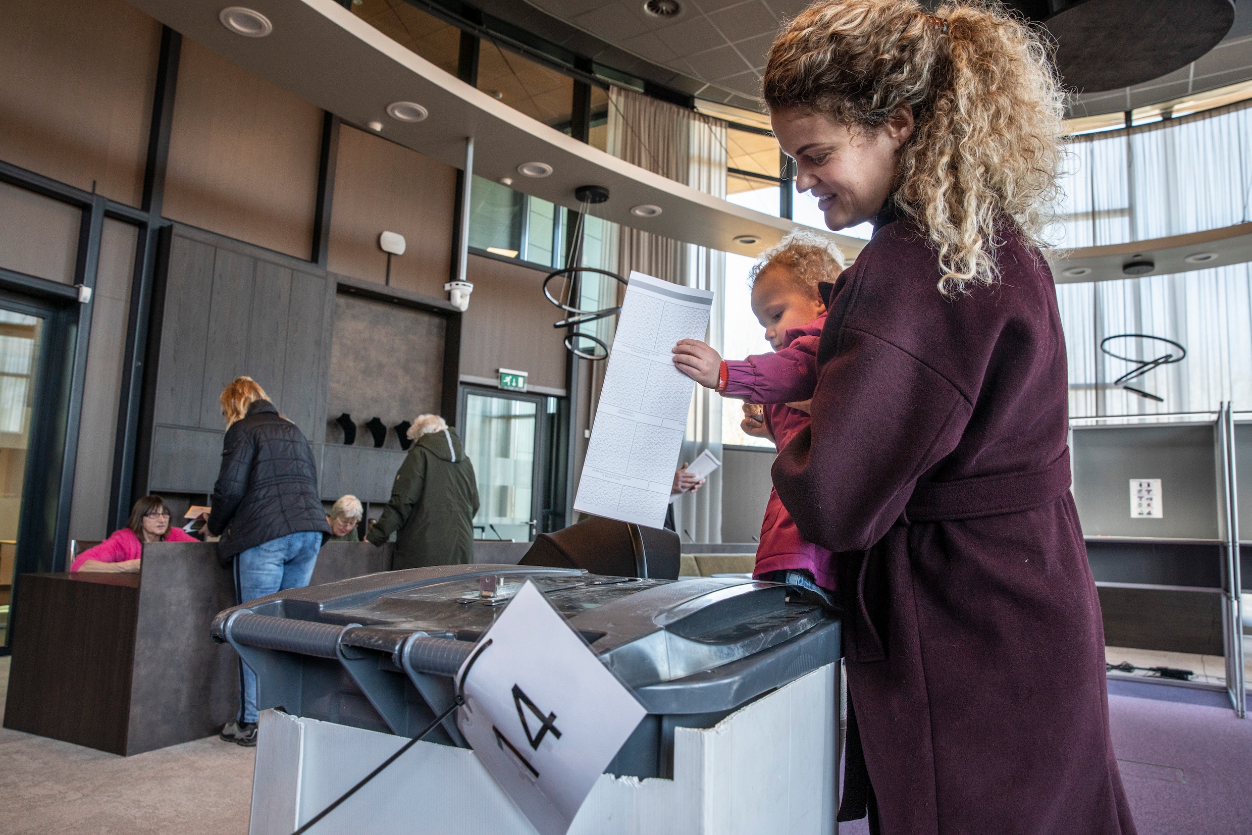 Een vrouw brengt met behulp van haar kind haar stem uit in de raadszaal van het gemeentehuis in Diever.