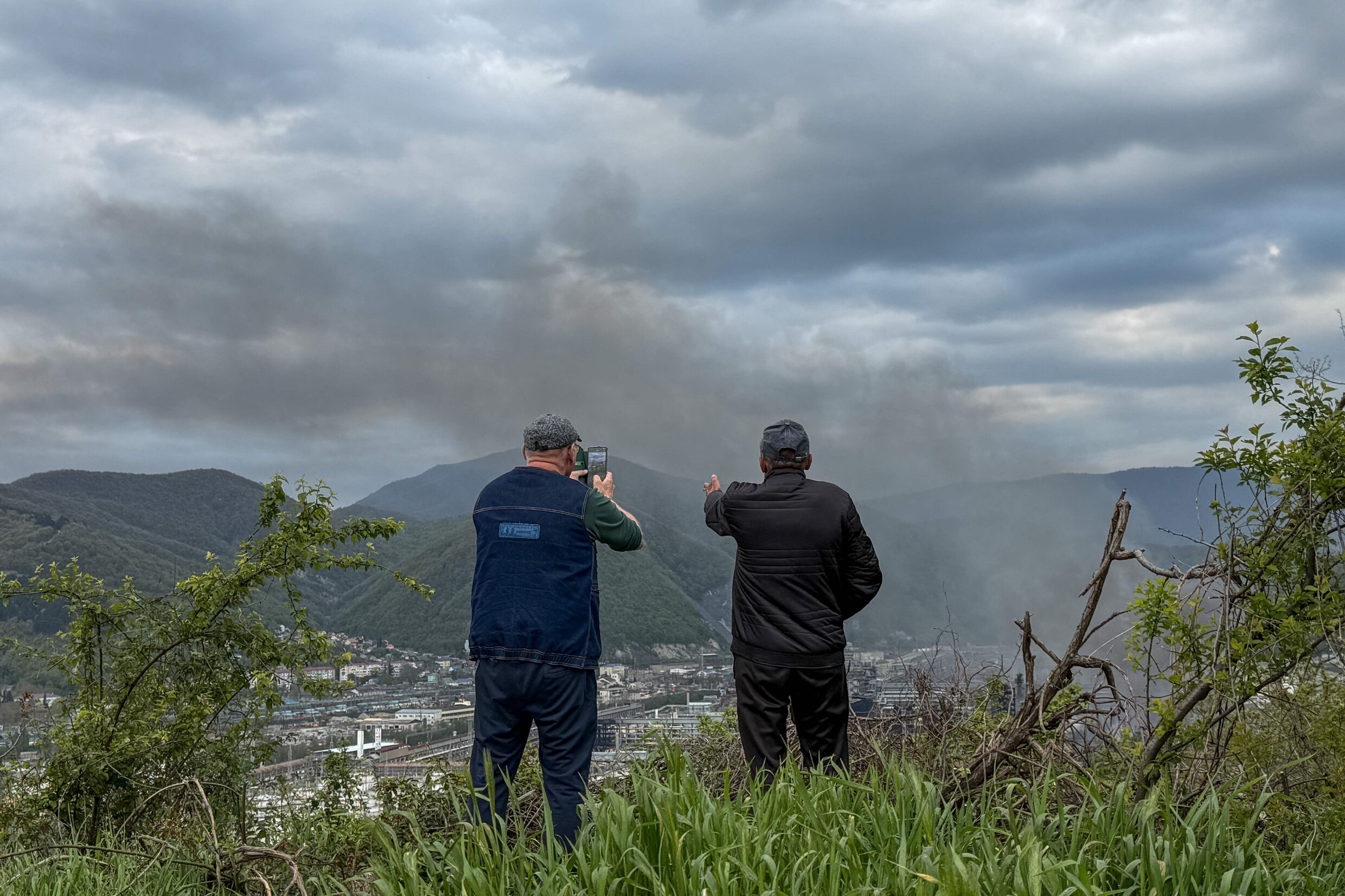 Inwoners van de Russische regio Krasnodar zien rook opstijgen boven Tuapse, na een aanval in april op een olieraffinaderij in de stad. 