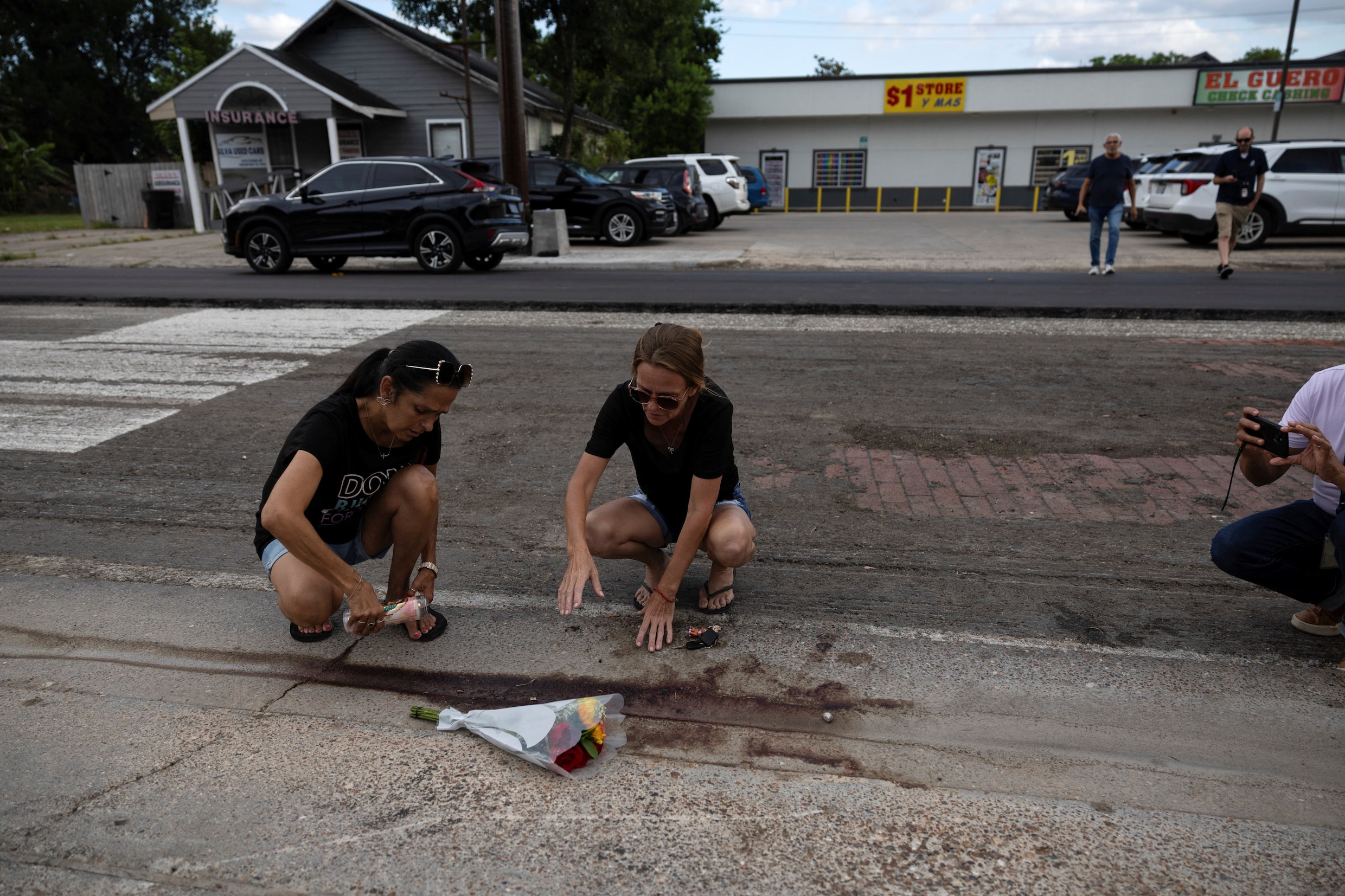 Twee vrouwen plaatsen een kaars naast bloemen op de plek waar een ICE-agent een automobilist doodschoot.