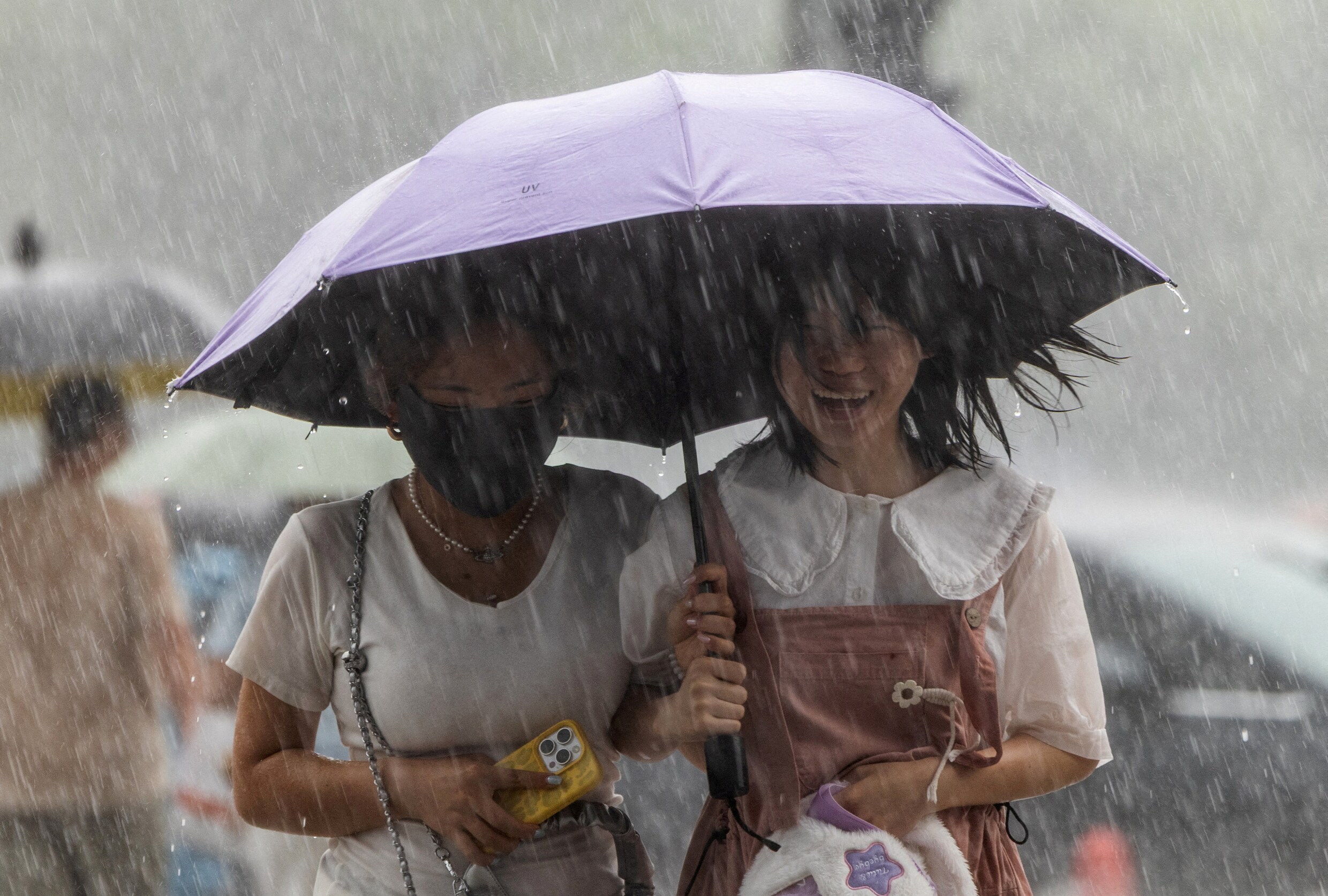 Twee vrouwen in Beijing schuilen onder hun paraplu tijdens een zware regenbui vorige maand.