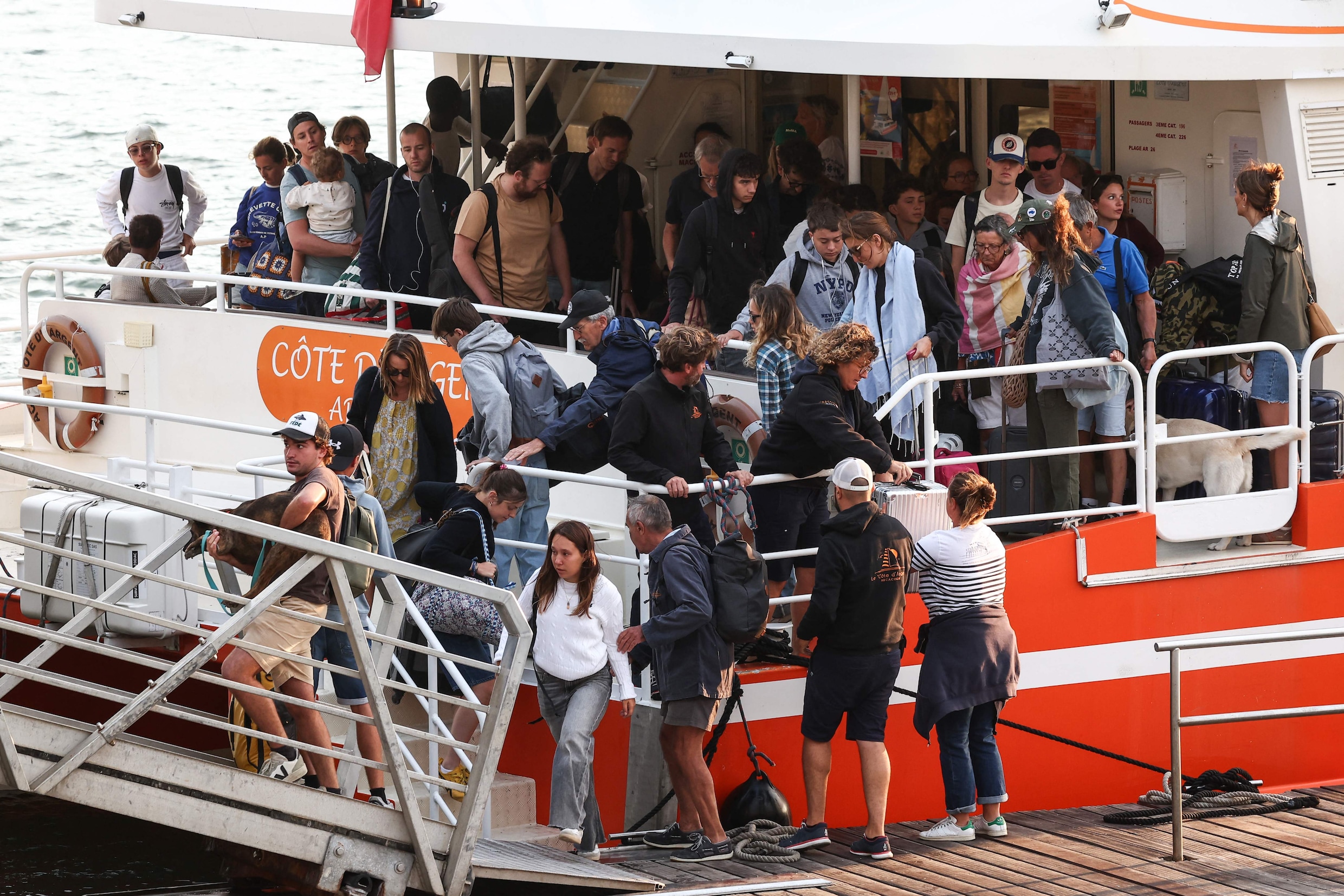 Mensen stappen van de boot af in Arcachon, aan de andere kant van de baai, nadat zij zijn geëvacueerd van Cap Ferret. 
