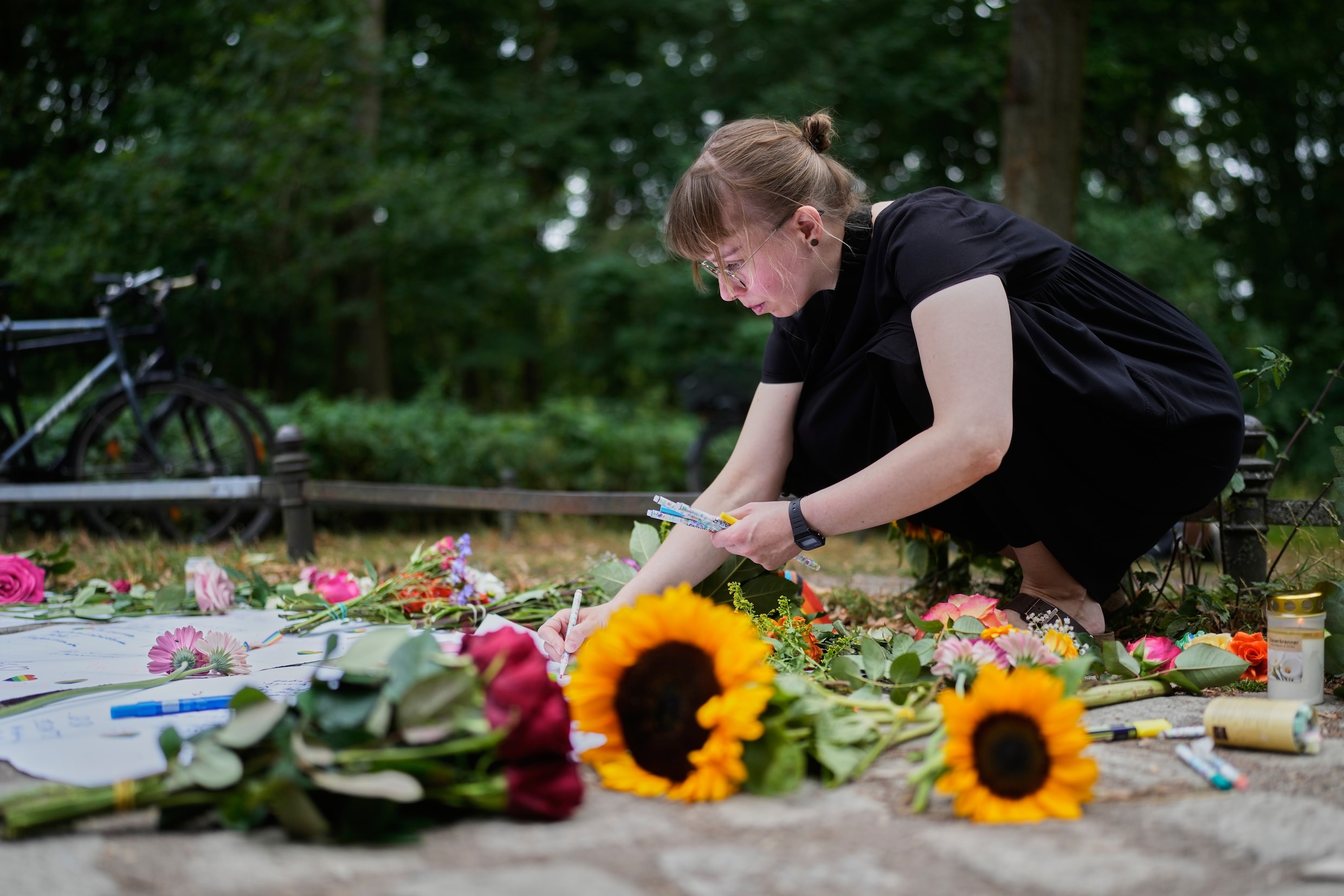 Een vrouw schrijft een boodschap bij een herdenkingsplek waar bloemen worden neergelegd, vlakbij de plek waar een busje inreed op bezoekers van de Pride. 