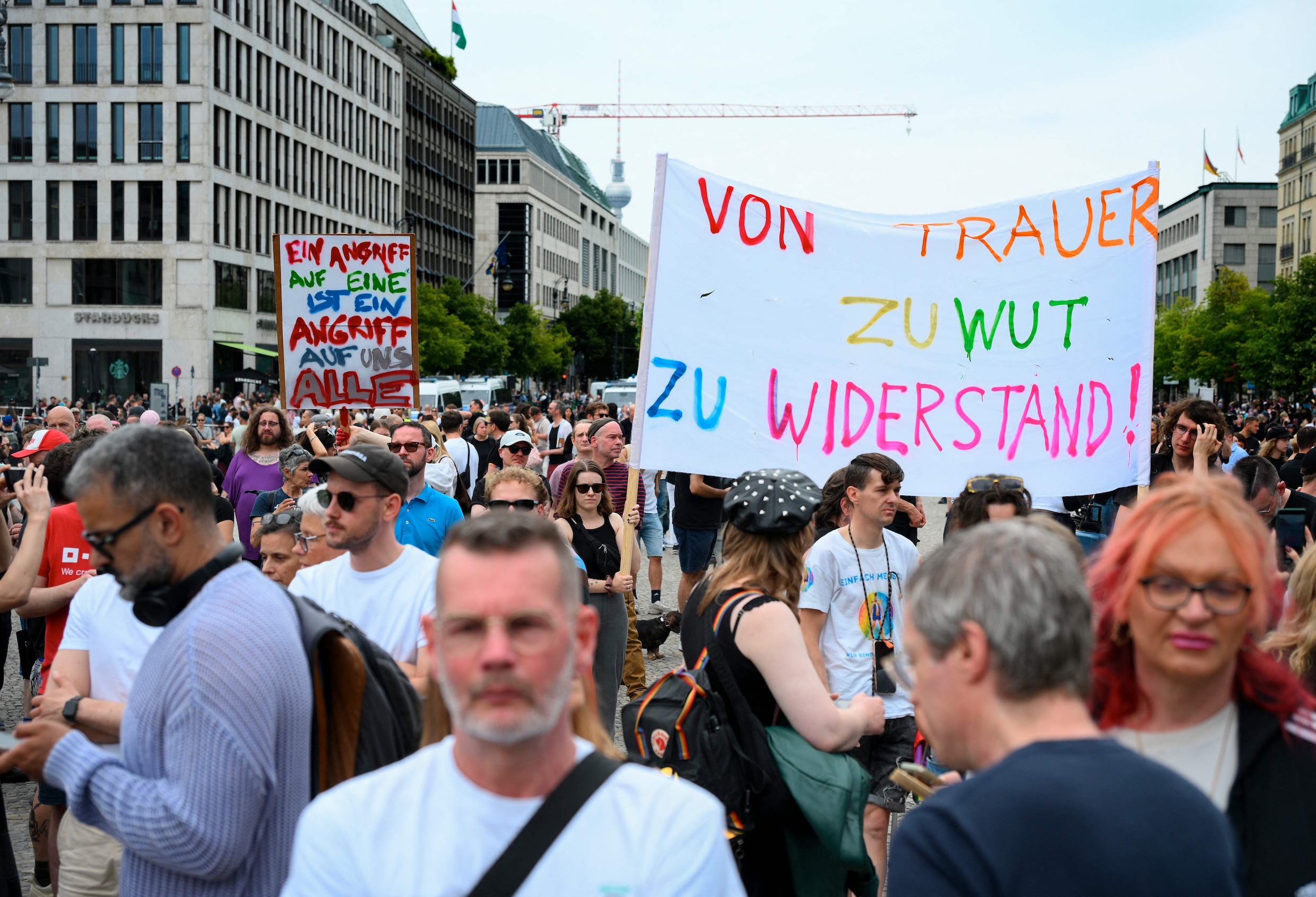 Mensen verzamelen zich zondag bij de Brandenburger Tor. Op het spandoek staat: ‘Van rouw, naar woede, naar verzet.’