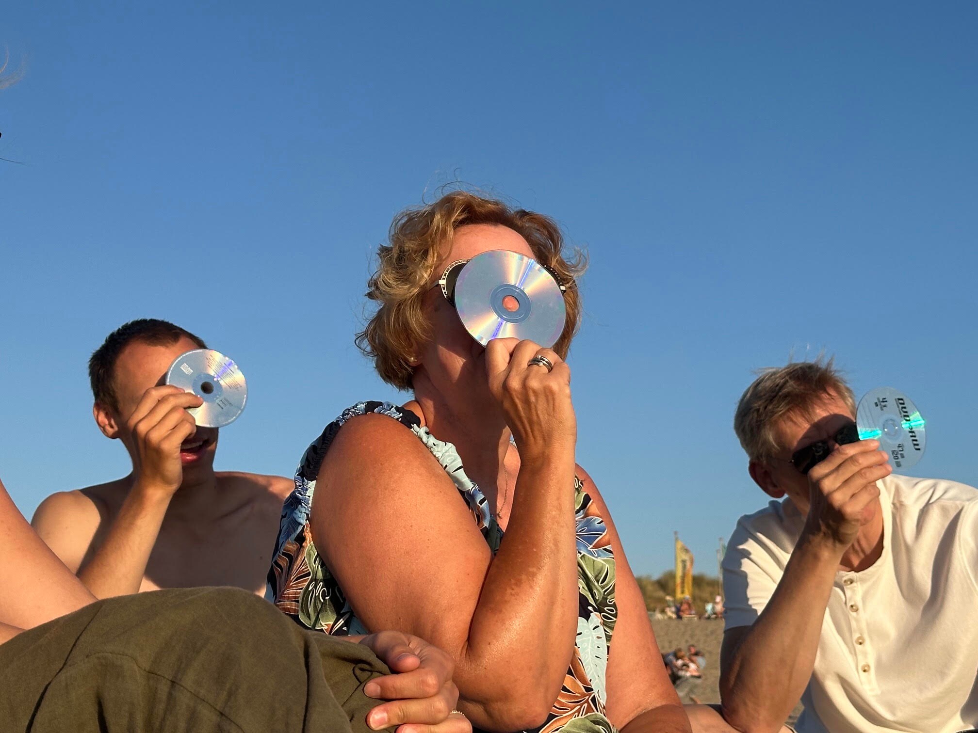 In Monster kijken mensen door cd’s naar de zonsverduistering.