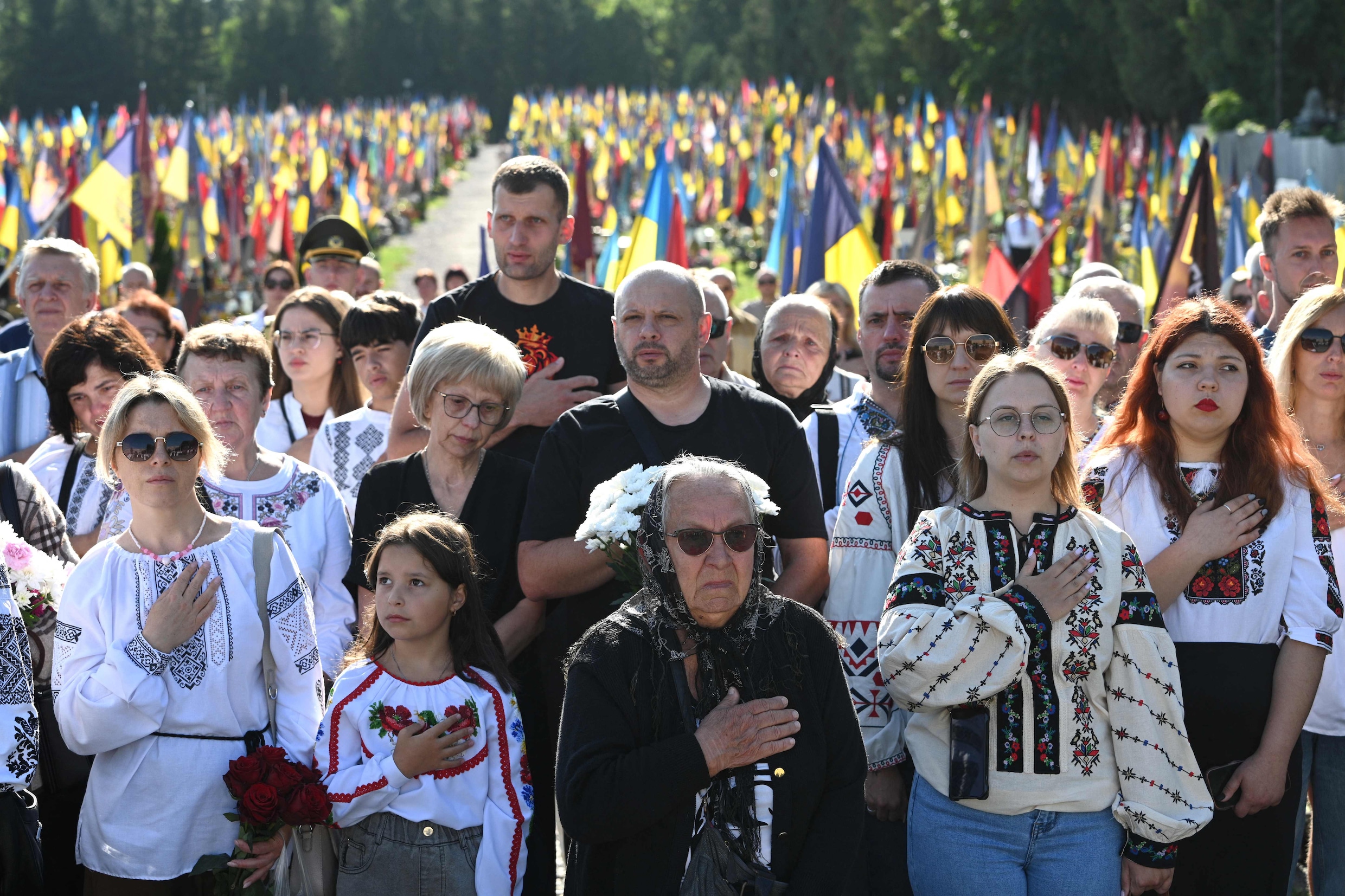 In de stad Lviv zingen mensen het Oekraïense volkslied terwijl ze gesneuvelde Oekraïense militairen herdenken op een begraafplaats.