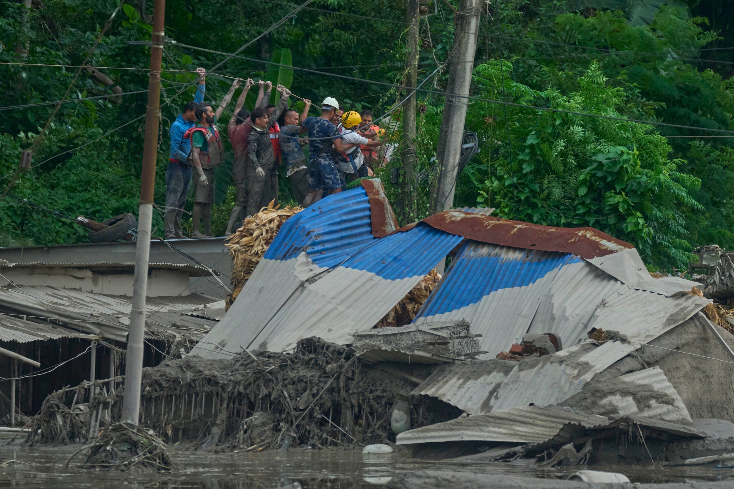 Reddingswerkers brengen een touwverbinding aan om in het getroffen gebied langs de Trishuli-rivier te zoeken naar overlevenden.