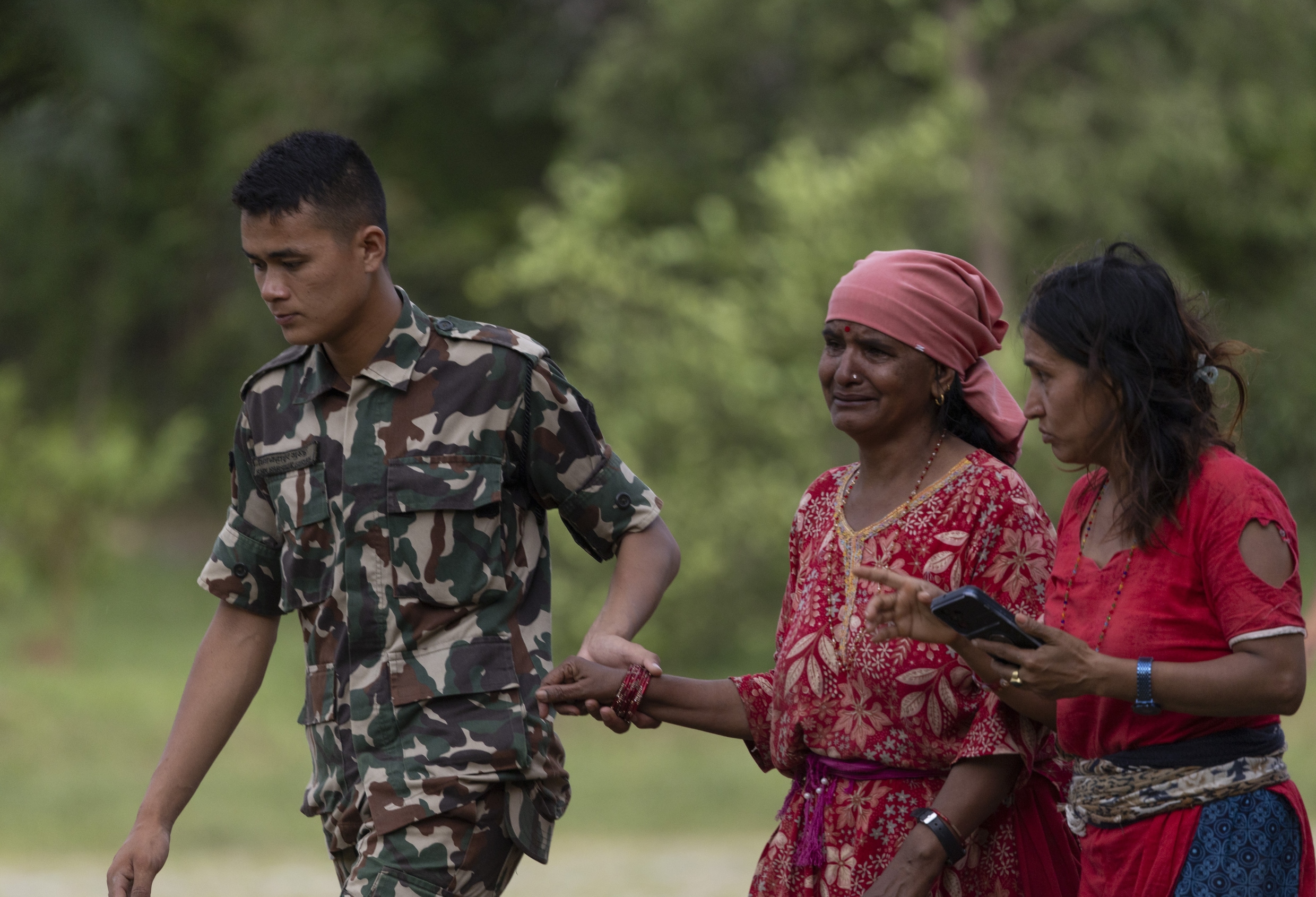 Een Nepalese militair ondersteunt inwoners van de getroffen regio Nuwakot.