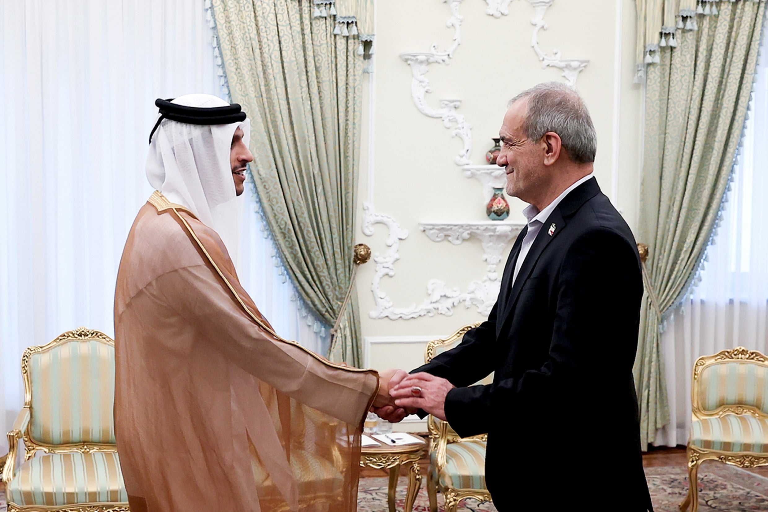 De Iranaanse president Masoud Pezeshkian (R) begroet de Qatarese premier sheik Mohammed bin Abdulrahman Al Thani, donderdag 27 augustus in Teheran.
