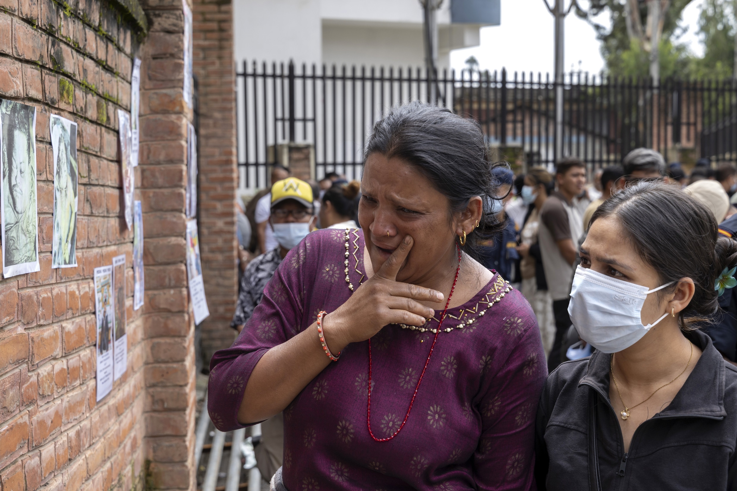Buiten een mortuarium in Kathmandu kijken familieleden van slachtoffers en vermisten van de ramp naar de foto’s van hun geliefden.