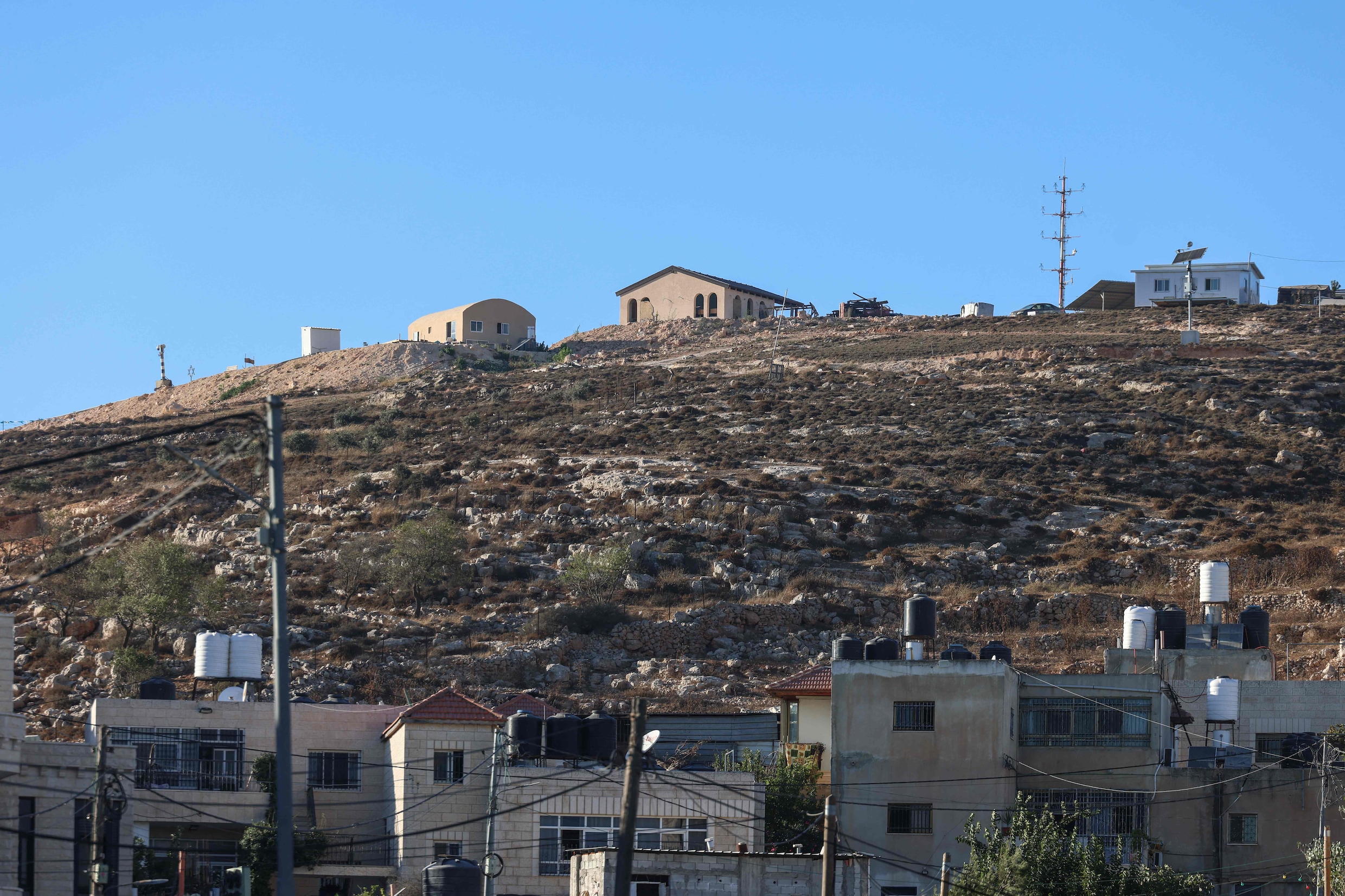 Huizen in het Palestijnse dorp Deir Jarir op de bezette Westelijke Jordaanoever, met daarboven een nieuwe Israëlische buitenpost.