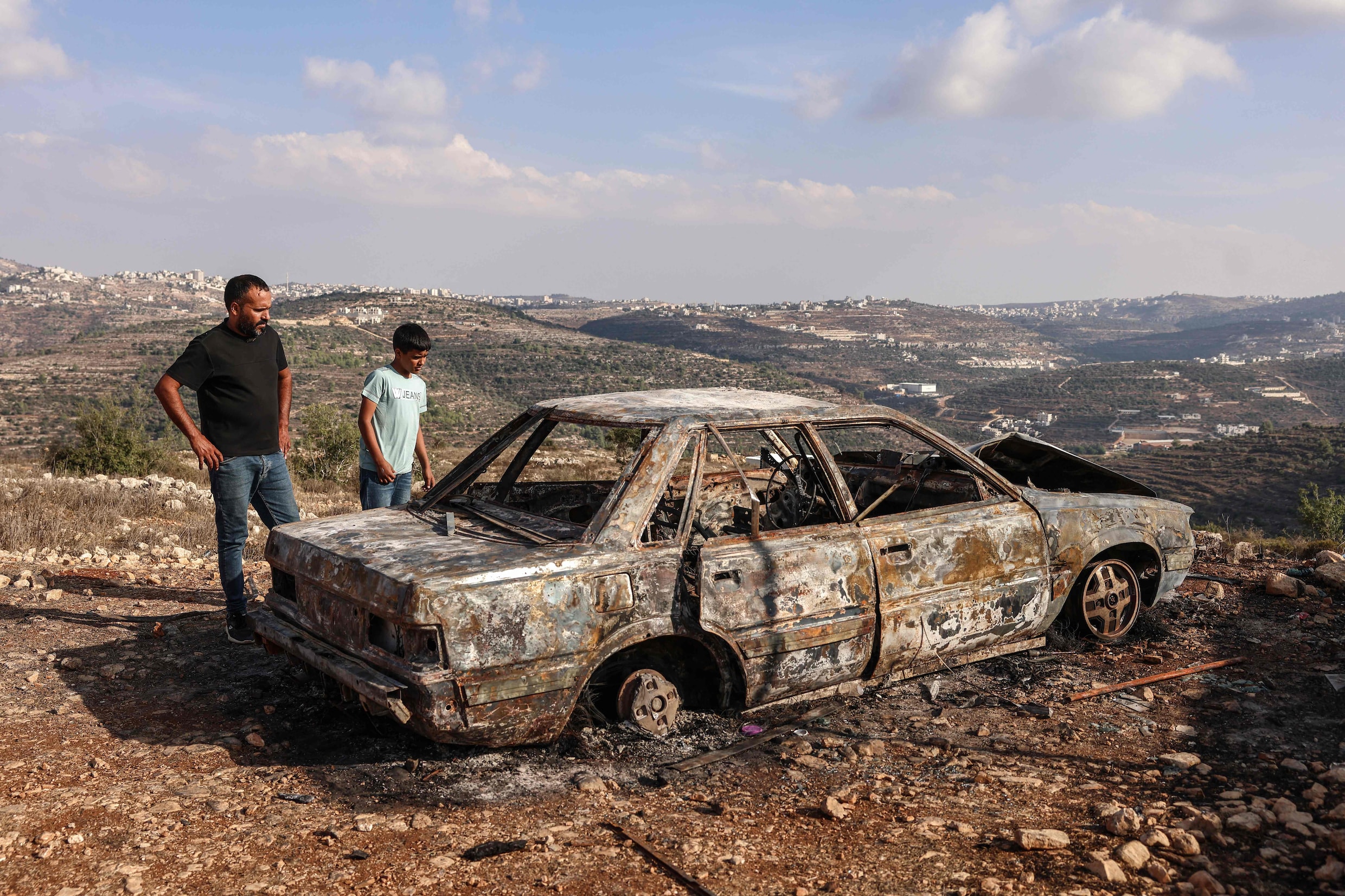 Palestijnen in de buurt van Ramallah, op de Westoever, bij een auto die door Israëlische kolonisten in brand is gezet. 