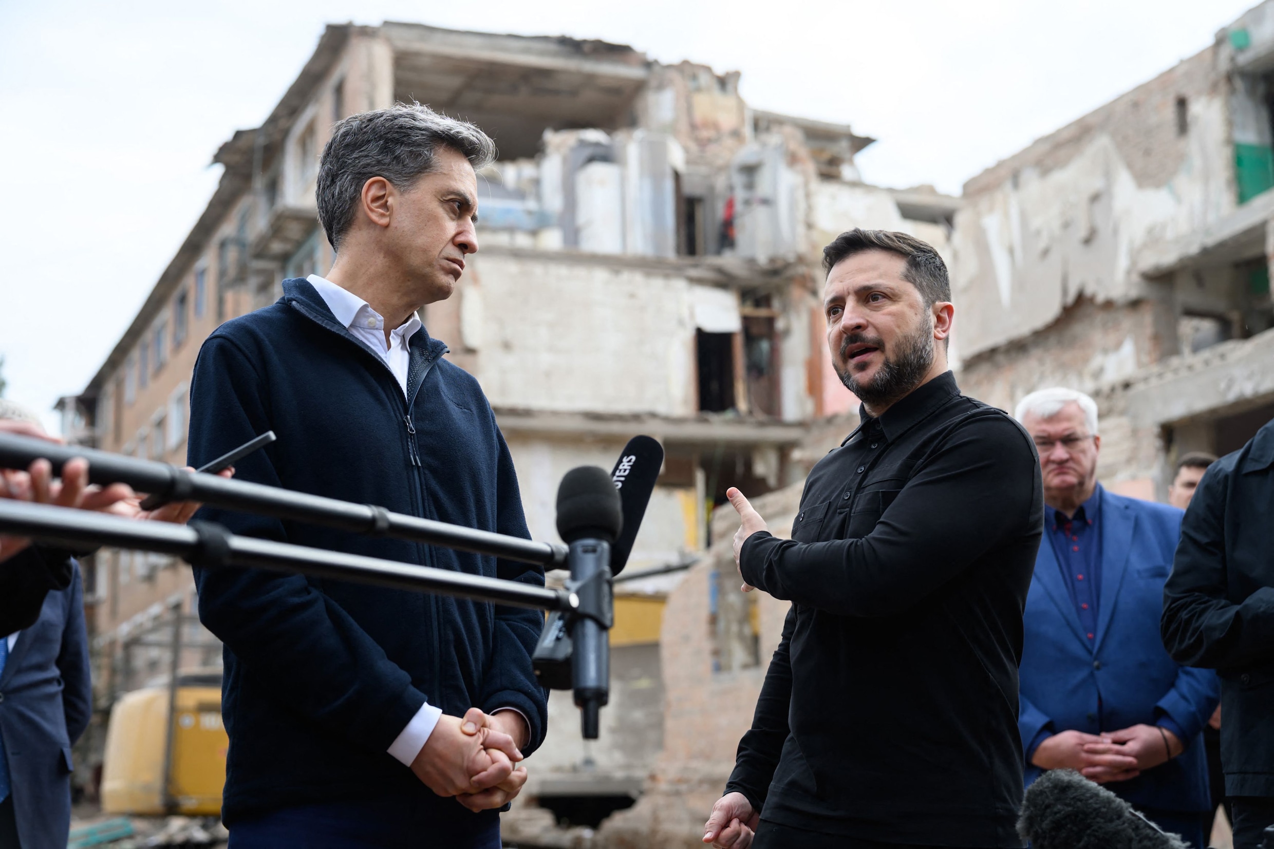 De Oekraïense president Volodymyr Zelensky met de Britse minister van Buitenlandse Zaken Ed Miliband (links) donderdag tijdens een bezoek aan de stad Pryloeky, waar een dag eerder 22 mensen om het leven kwamen bijeen Russische raketaanval op een appartementengebouw.