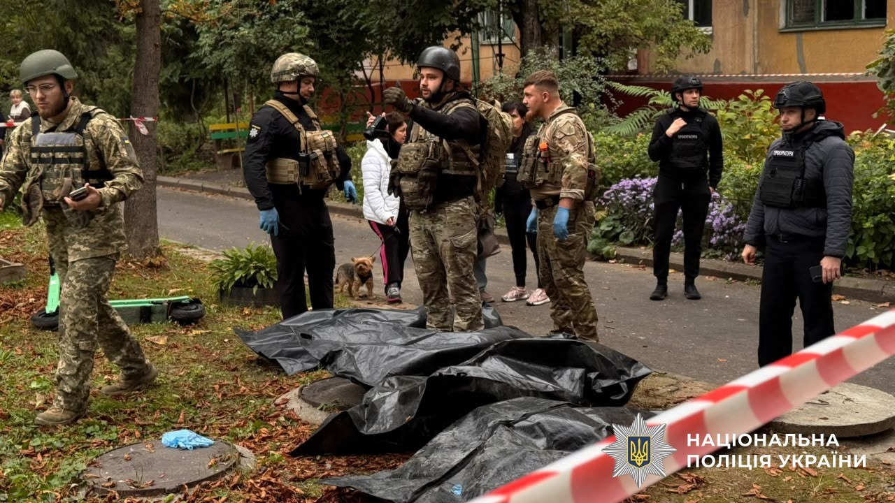 Oekraïense politie-agenten en militairen staan naast de afgedekte lichamen van mensen die bij de aanval op een woongebouw in Zaporizja vannacht omkwamen. 
