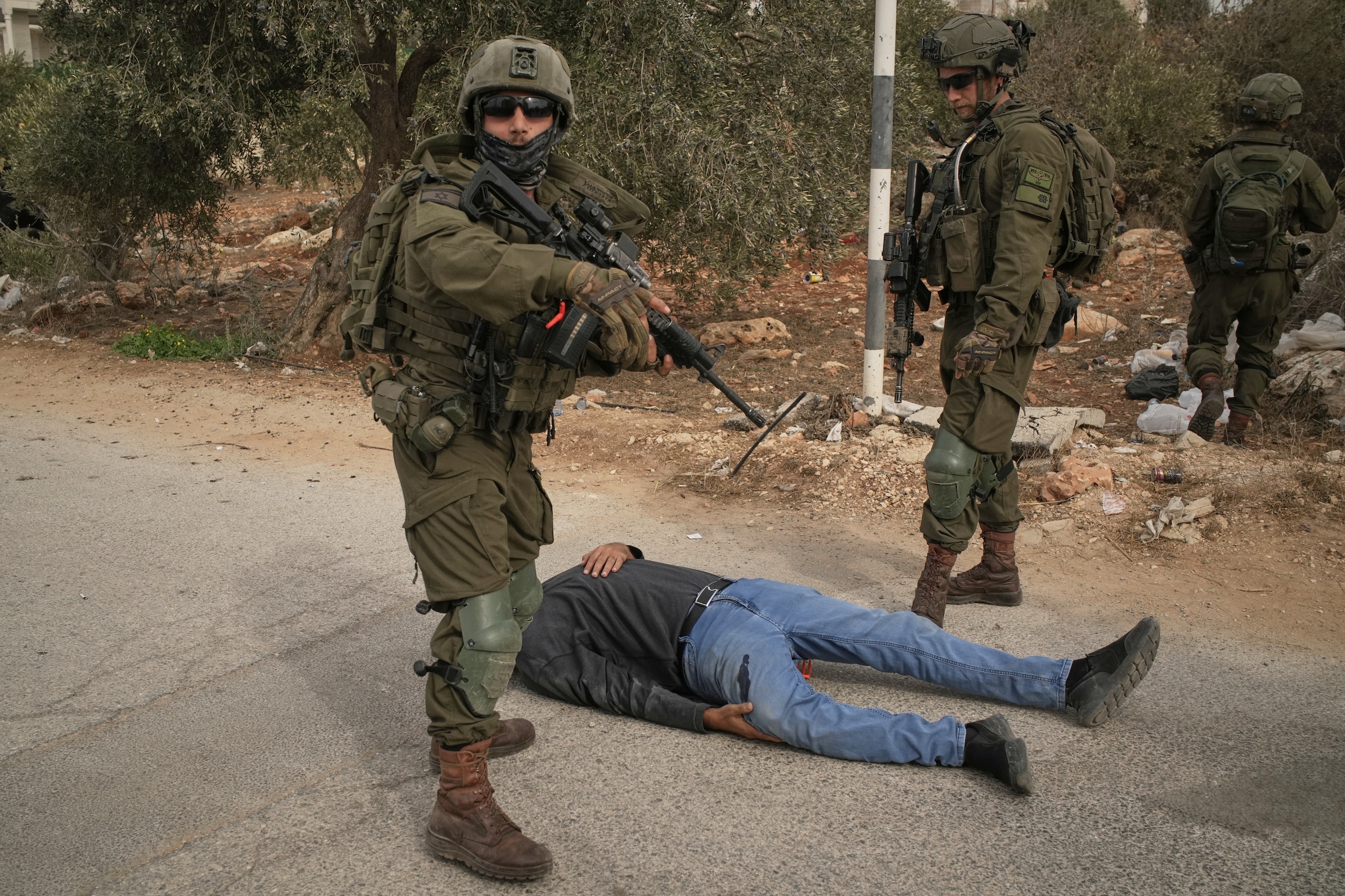 Israëlische militairen in Abu Falah naast een gewonde Palestijnse man, die door kogels werd geraakt. 