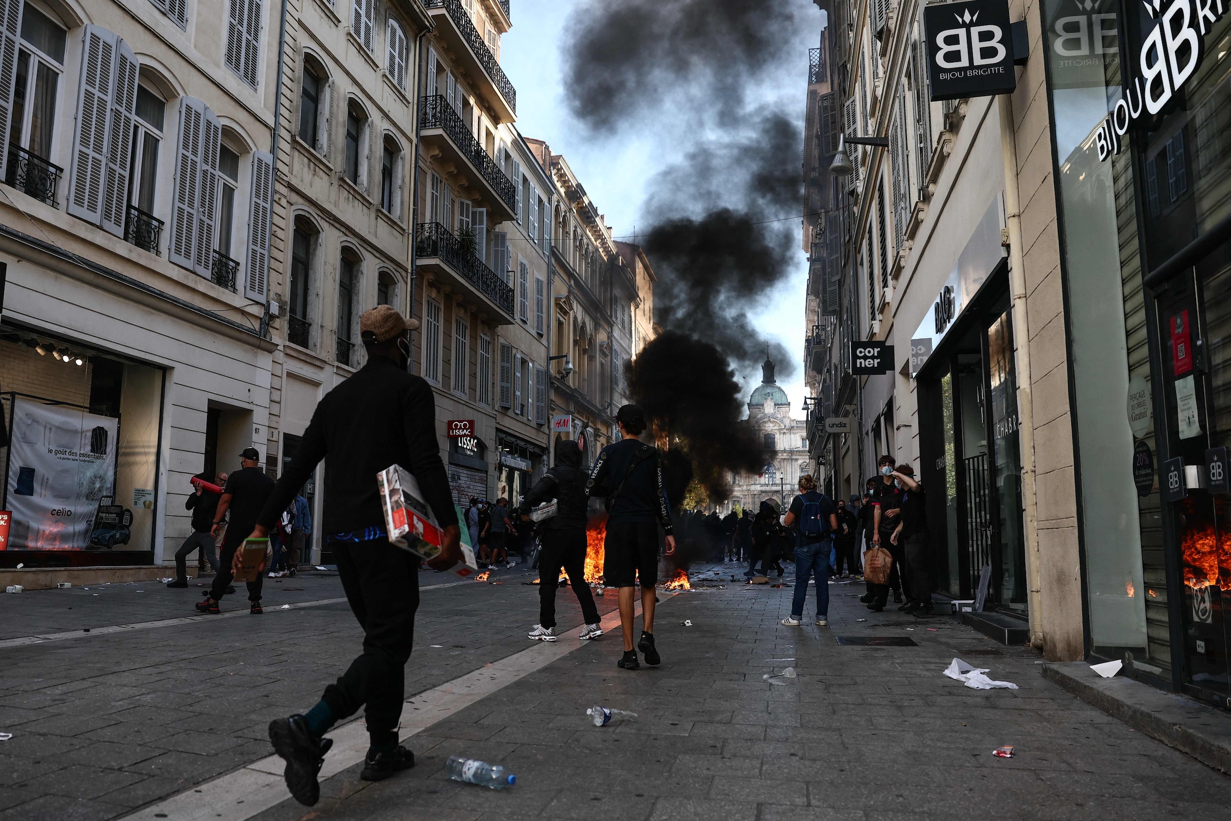Mensen dragen vermoedelijk uit winkels buitgemaakte spullen mee tijdens een demonstratie tegen de hoge kosten van levensonderhoud in het centrum van Marseille.
