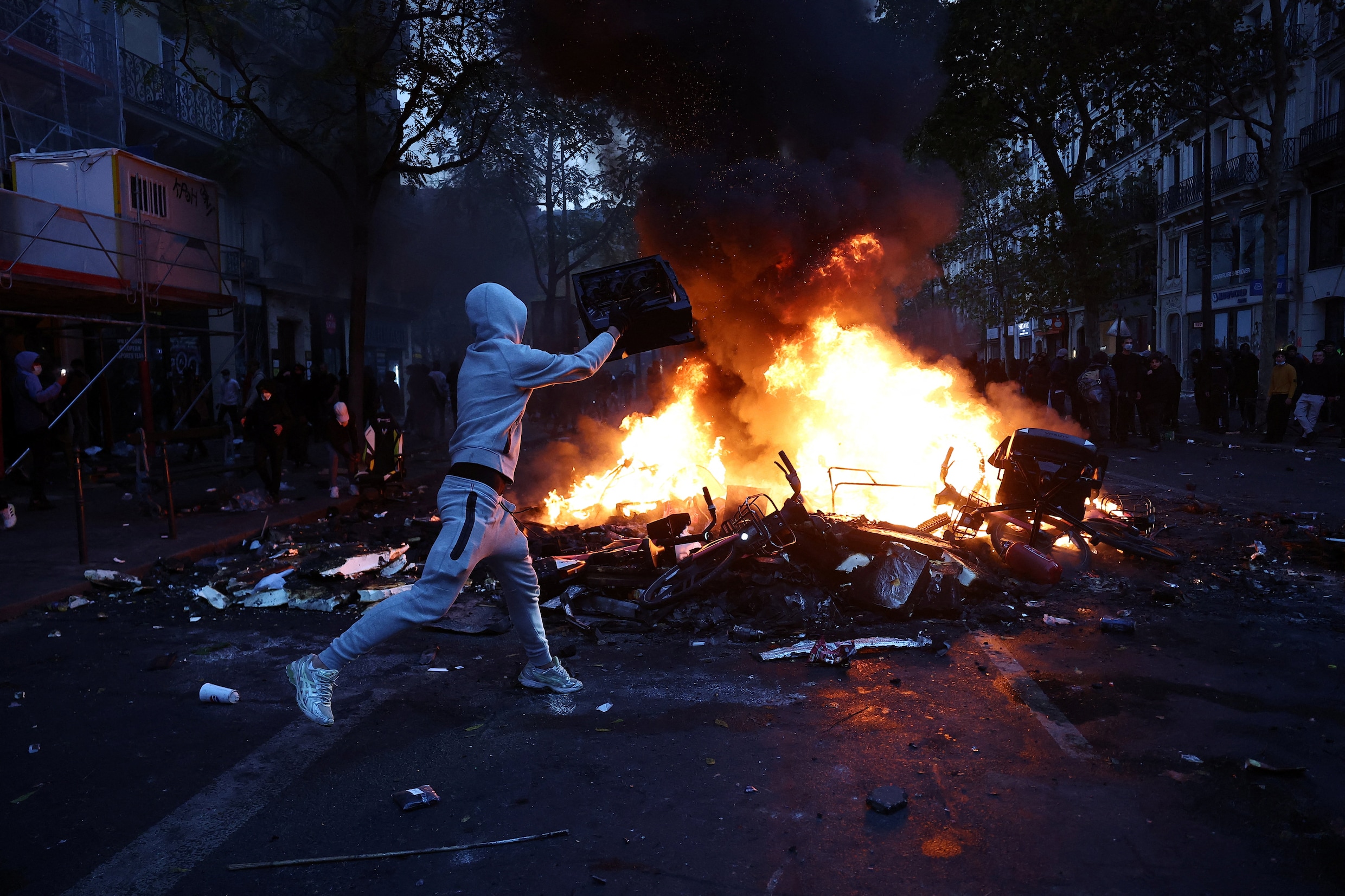 Een demonstrant gooit een object in een brandende barricade. 
