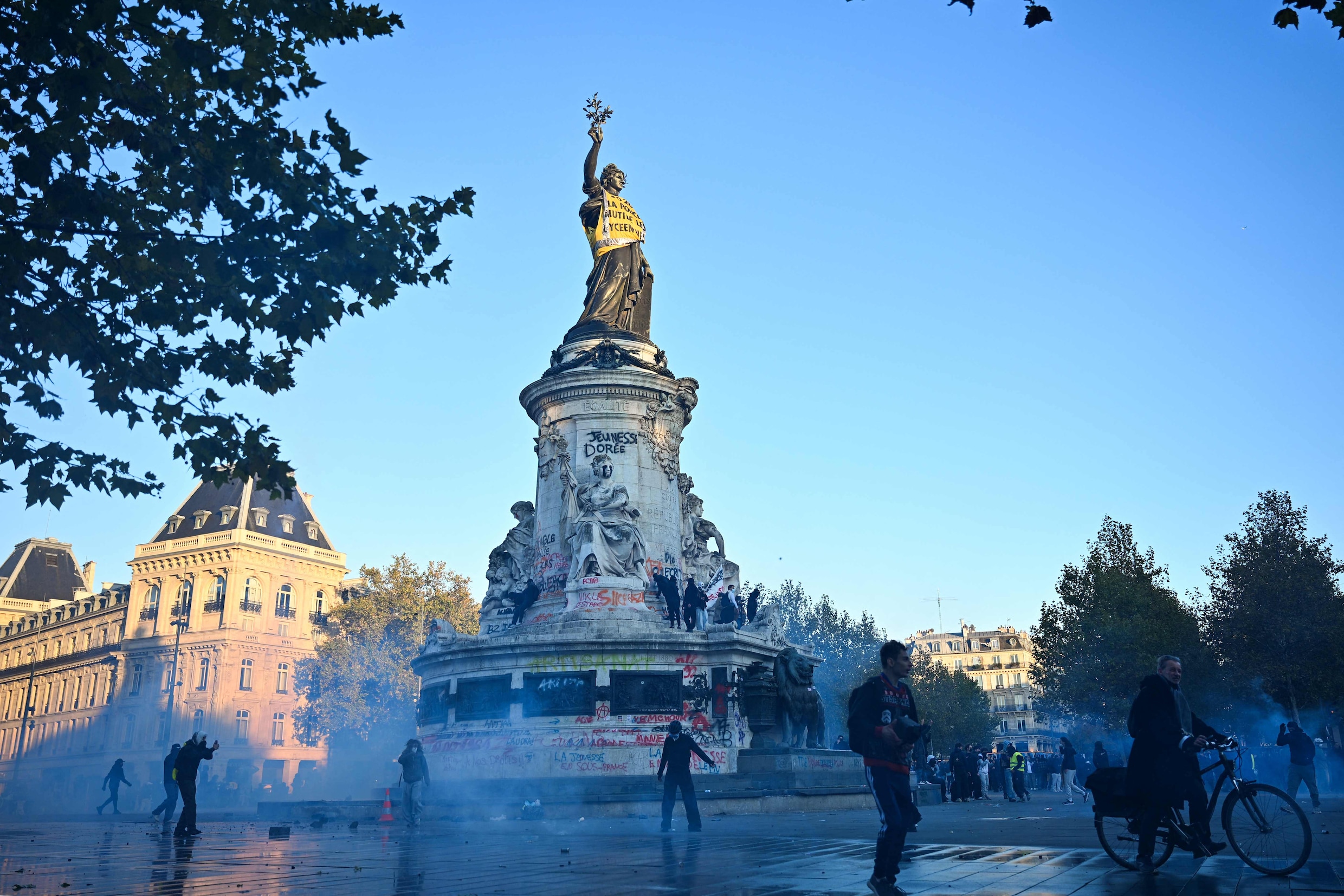 Betogers lopen door traangaswolken op het Place de la République in Parijs vandaag. 