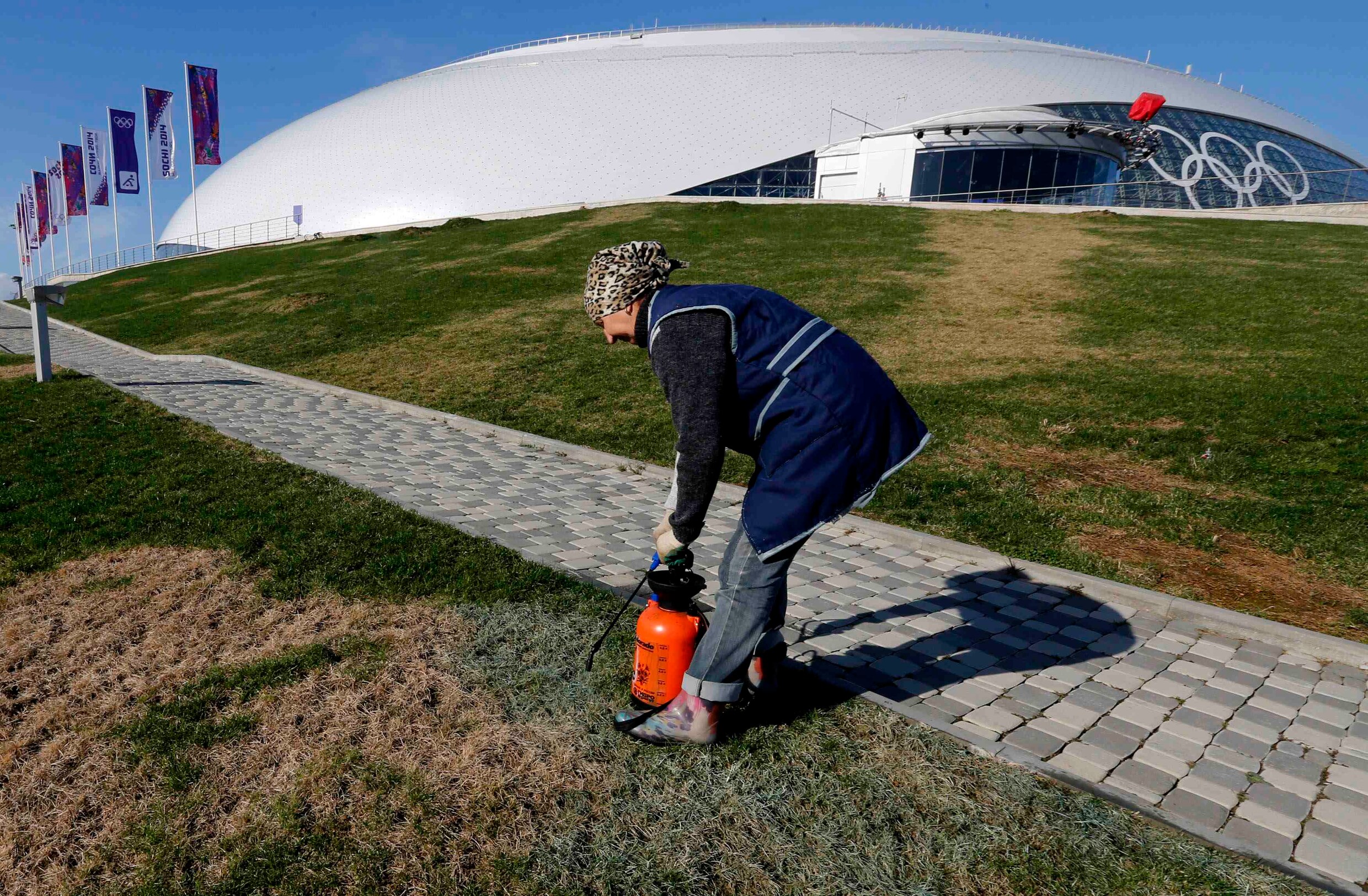 Een vrouw pept dinsdag het gras voor de Bolshoy Ice Dome in Sotsji op.