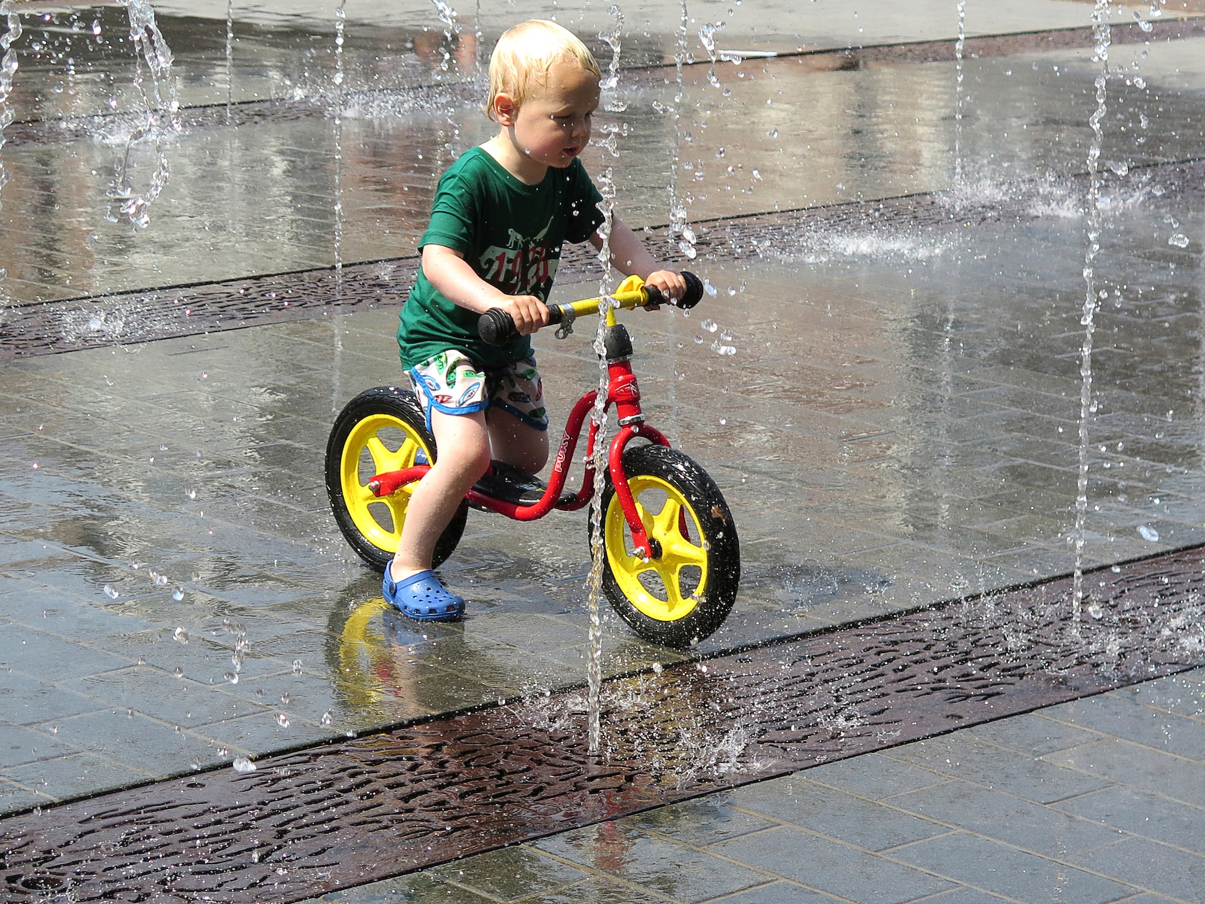 Een jongetje fiets door het water in Amsterdam.