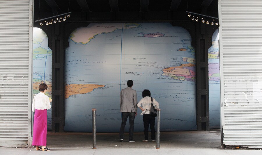 Mensen kijken naar de kunstzinnige wereldbol 'Tight Spot' van David Byrne in New York.